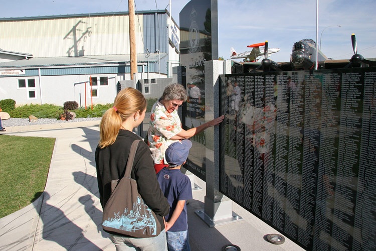 Marg Liessens showing Riley and Sarah Watson her fathers name (Albert Dorey) on the <br />Nanton Bomber Command Memorial Wall.