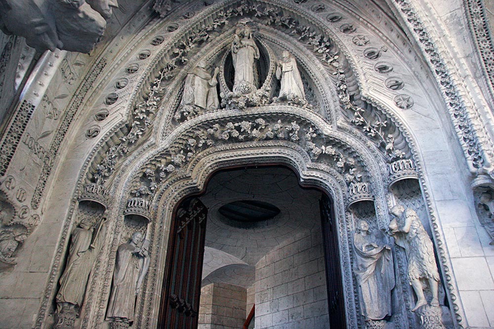this is the "Rose Tree door", and the only part of the cloister that Gaudi <br />was able to complete in his lifetime. It is renowned for its exquisite <br />stonework and the massive wooden door...
